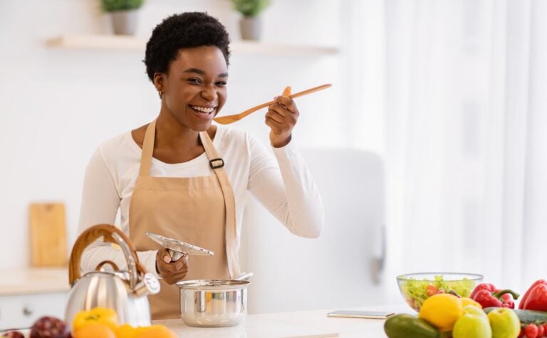 a women tastes a spoon while she cooks up a dish in a pot